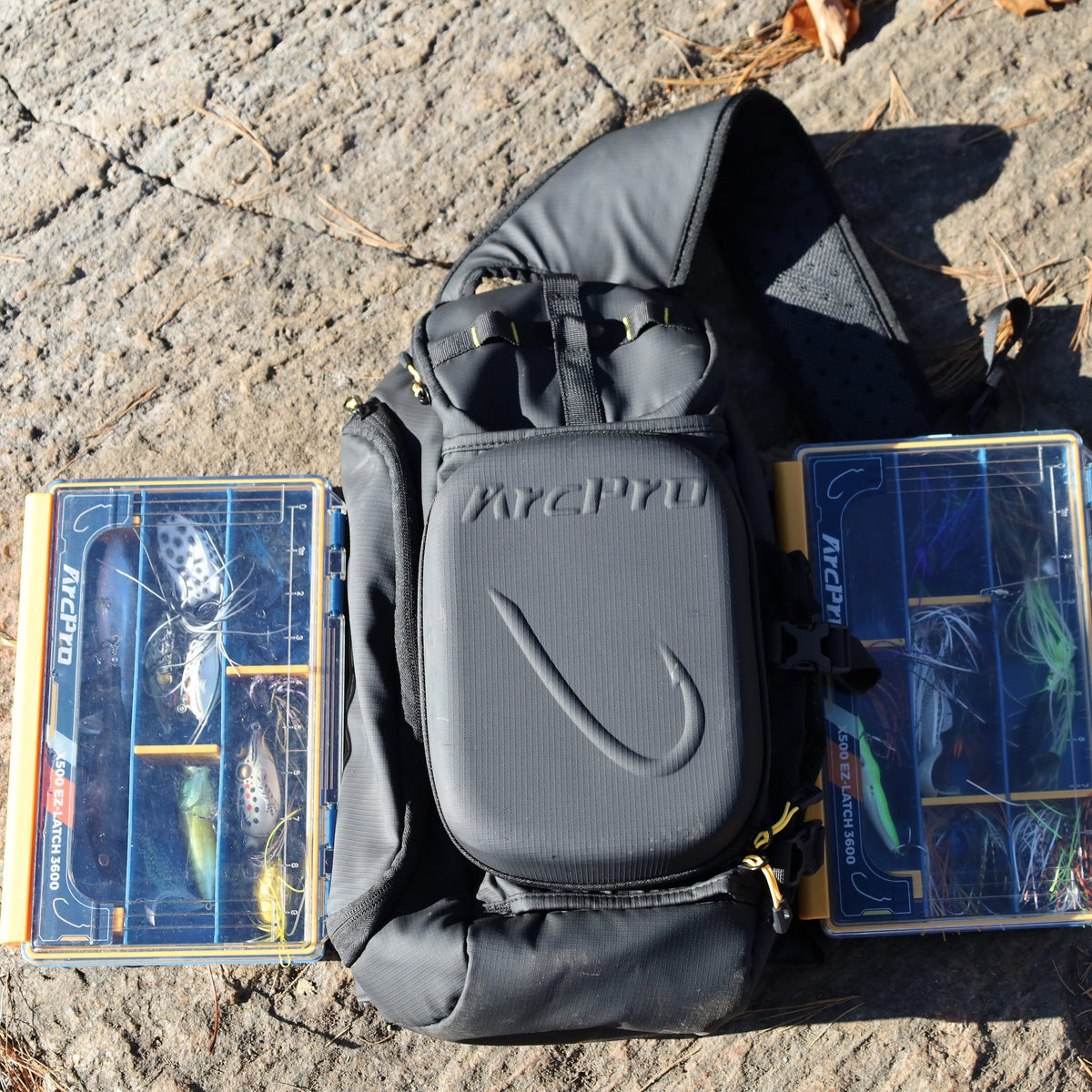 ArcPro EVA sling pack with two 3600 waterproof tackle boxes, laid out on a lakeside rock